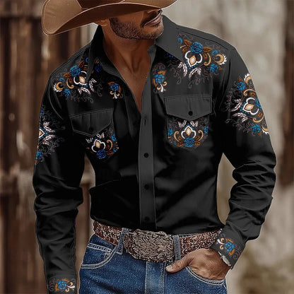 Man wearing a black embroidered shirt with floral patterns, blue jeans, and a cowboy hat.