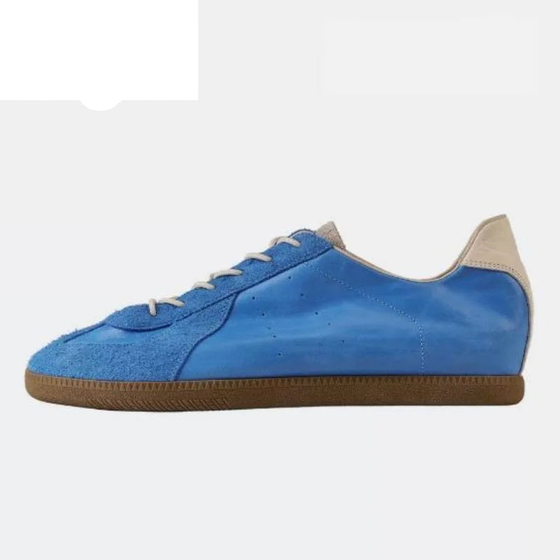 A blue suede and leather low-top sneaker with white laces, a beige heel tab, and a brown gum sole, shown on a light gray background with the Pinyue brand logo in the top-left corner.