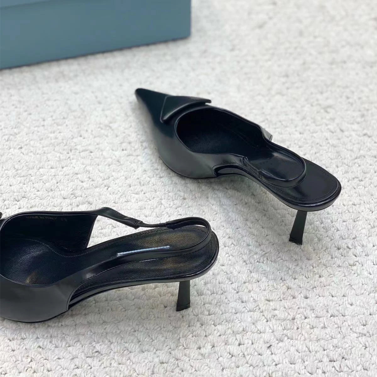 Black high-heeled shoes on a textured white surface