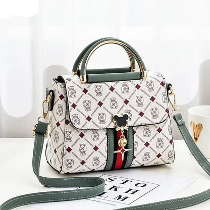 Designer handbag with patterned design and Mickey Mouse charm on a white surface.
