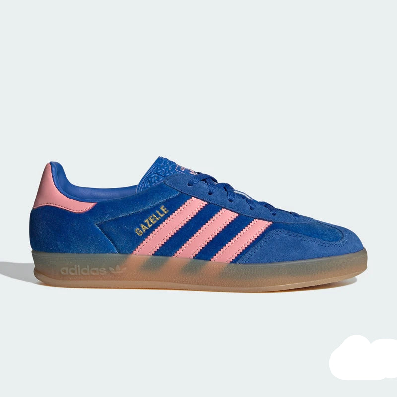 A blue Adidas Gazelle sneaker with pink three-stripes and heel tab, featuring a translucent gum sole, shown in a side profile on a light gray background.