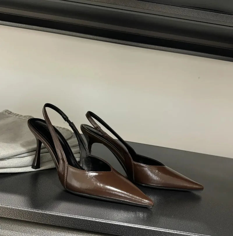 Pair of brown high-heeled shoes on a black surface with a neutral background