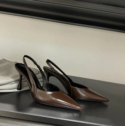 Pair of brown high-heeled shoes on a black surface with a neutral background