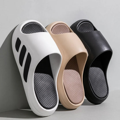 Three pairs of slides in white, beige, and black on a gray background