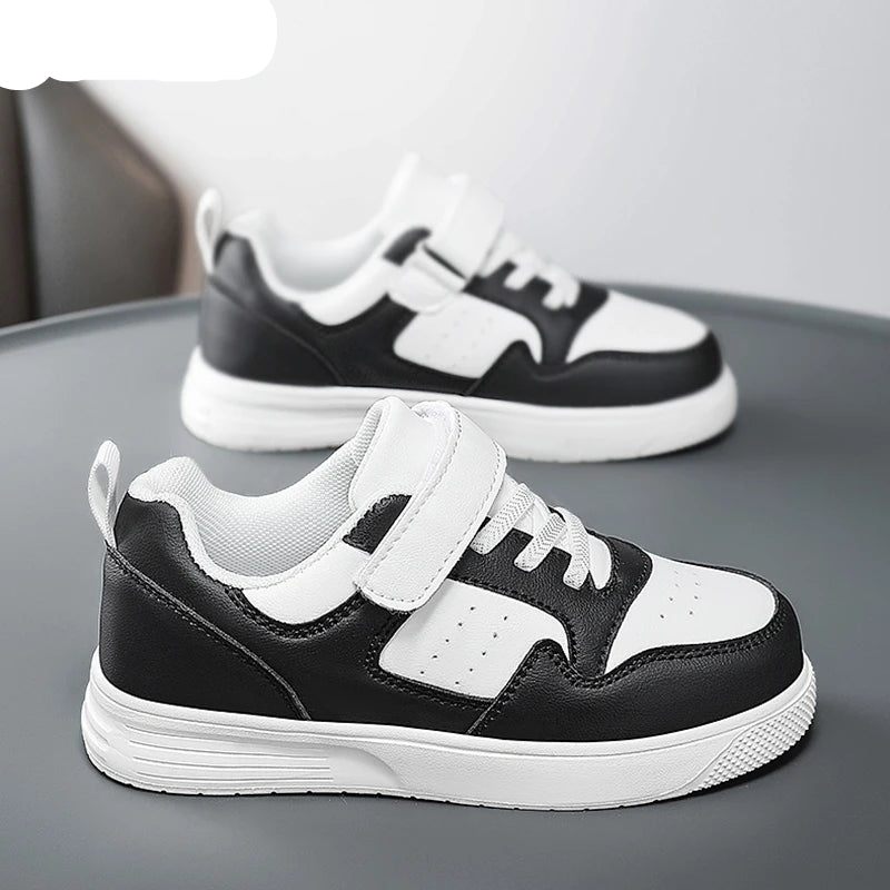 A pair of children's low-top sneakers in black and white, featuring a hook-and-loop strap closure and white soles. The brand name NBGAGA is visible in the top left corner.