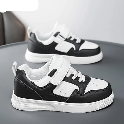 A pair of children's low-top sneakers in black and white, featuring a hook-and-loop strap closure and white soles. The brand name NBGAGA is visible in the top left corner.
