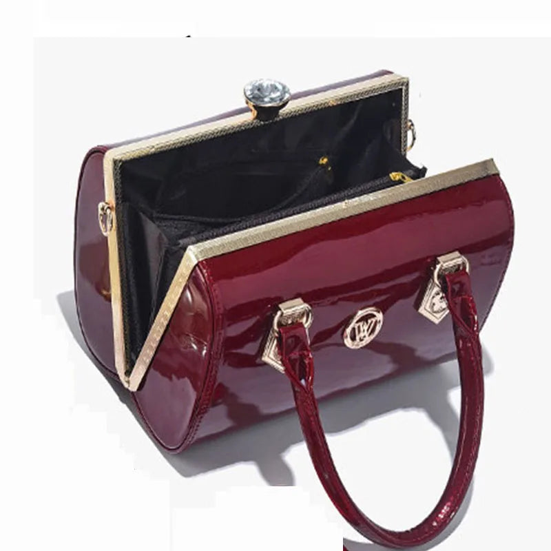 Red patent leather handbag with gold accents on a white background