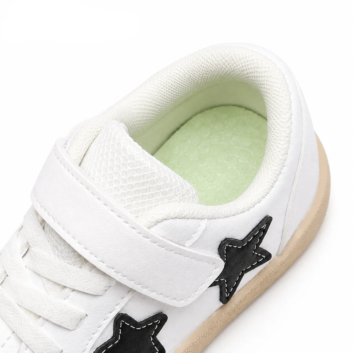 White PmwRun children's low-top sneaker with a hook-and-loop strap, black star accents, and a light beige gum sole, shown on a white background.