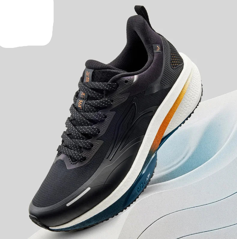 A 361° athletic sneaker in black and dark gray with a thick white midsole and orange accents, shown on a light gray background with a white curved platform.