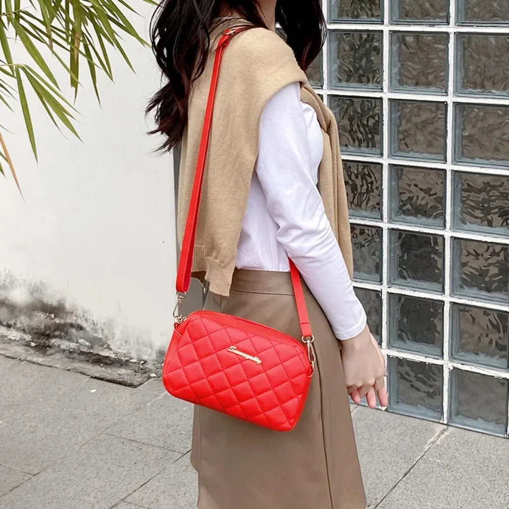 Person wearing a beige vest and holding a red quilted handbag in front of a glass-block wall.