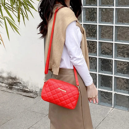 Person wearing a beige vest and holding a red quilted handbag in front of a glass-block wall.