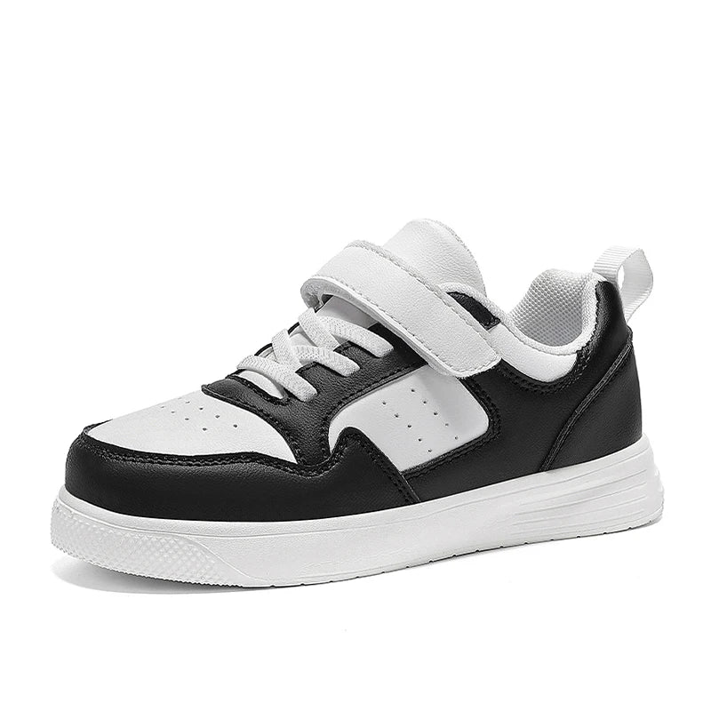 A black and white low-top sneaker with a hook-and-loop strap closure, white laces, and a thick white sole, shown from a side profile on a white background.