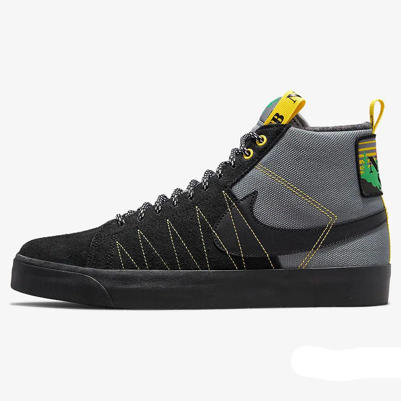 A Nike high-top sneaker in black and gray suede and mesh, featuring yellow contrast stitching, a yellow pull tab, and a green and yellow heel accent, shown against a light gray background.