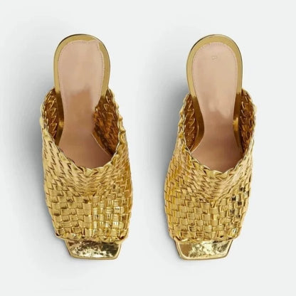 Pair of gold woven high-heeled shoes on a light gray background